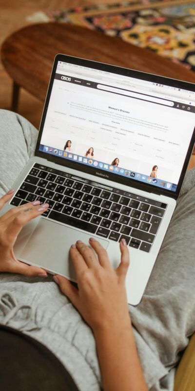 Person browsing an online shopping website on a laptop while relaxing indoors.